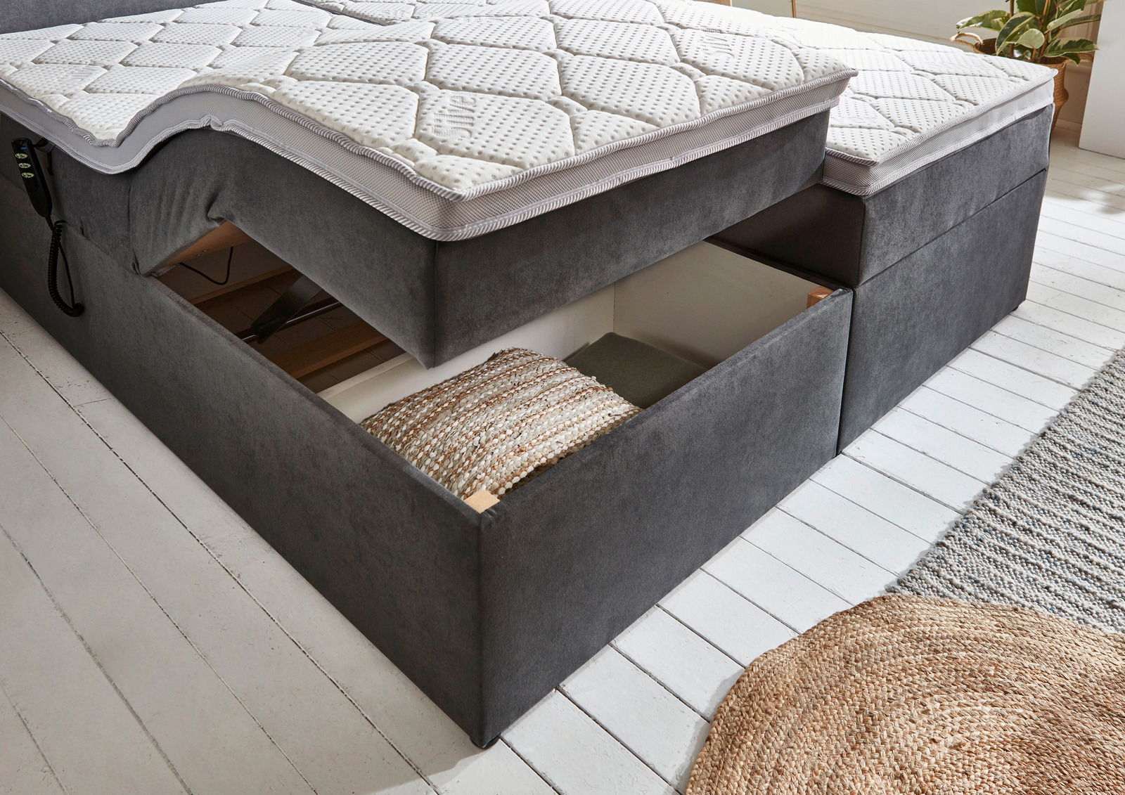 Boxbett mit Motor, seitliche Perspektive, mit geöffneter Schublade zur Aufbewahrung.