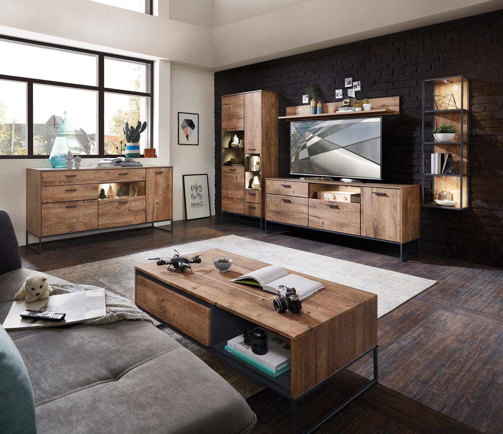 Wohnzimmeransicht mit moderner Holzmöbelkombination, bestehend aus Sideboard, Vitrine und TV-Unterteil, in einem hellen Raum mit großen Fenstern.