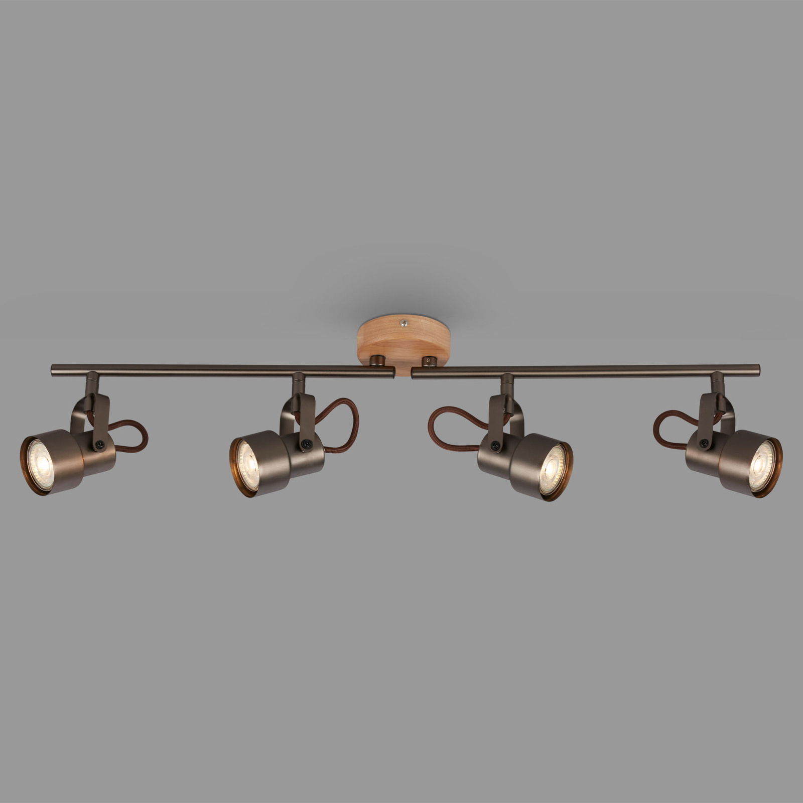 Moderne Spotleuchte mit vier verstellbaren Strahlern, montiert auf einer Holzhalterung, seitliche Perspektive.