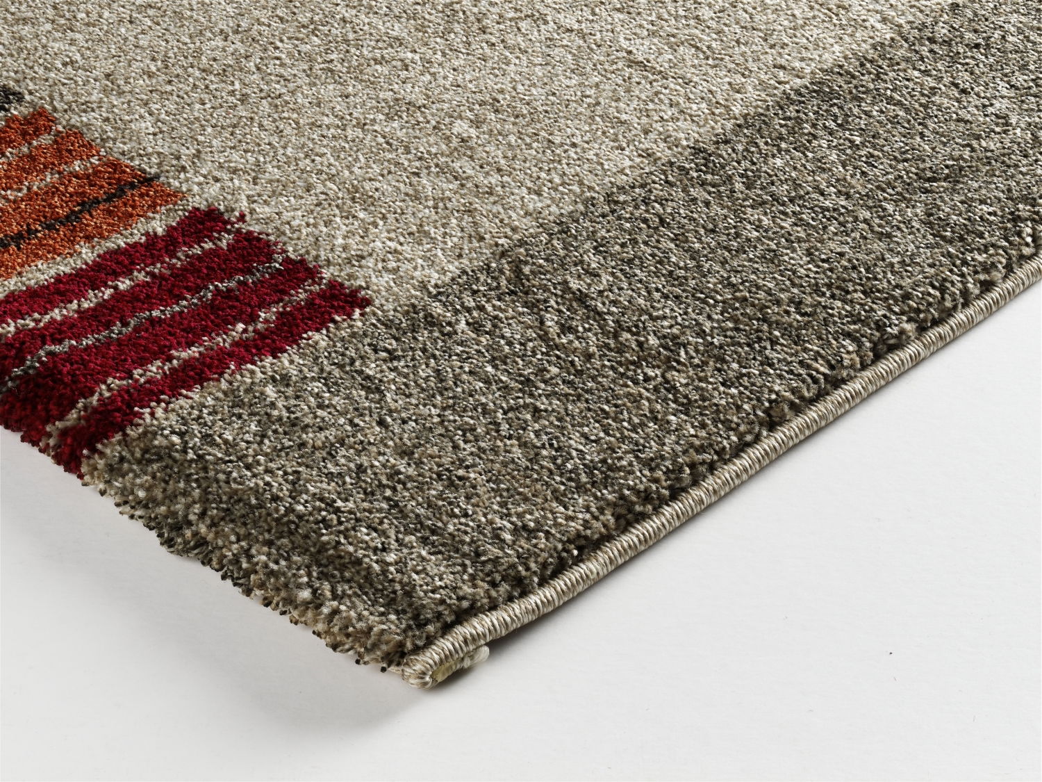 Nahaufnahme einer Ecke eines Teppichs mit grauen und roten Streifen, Perspektive von oben.
