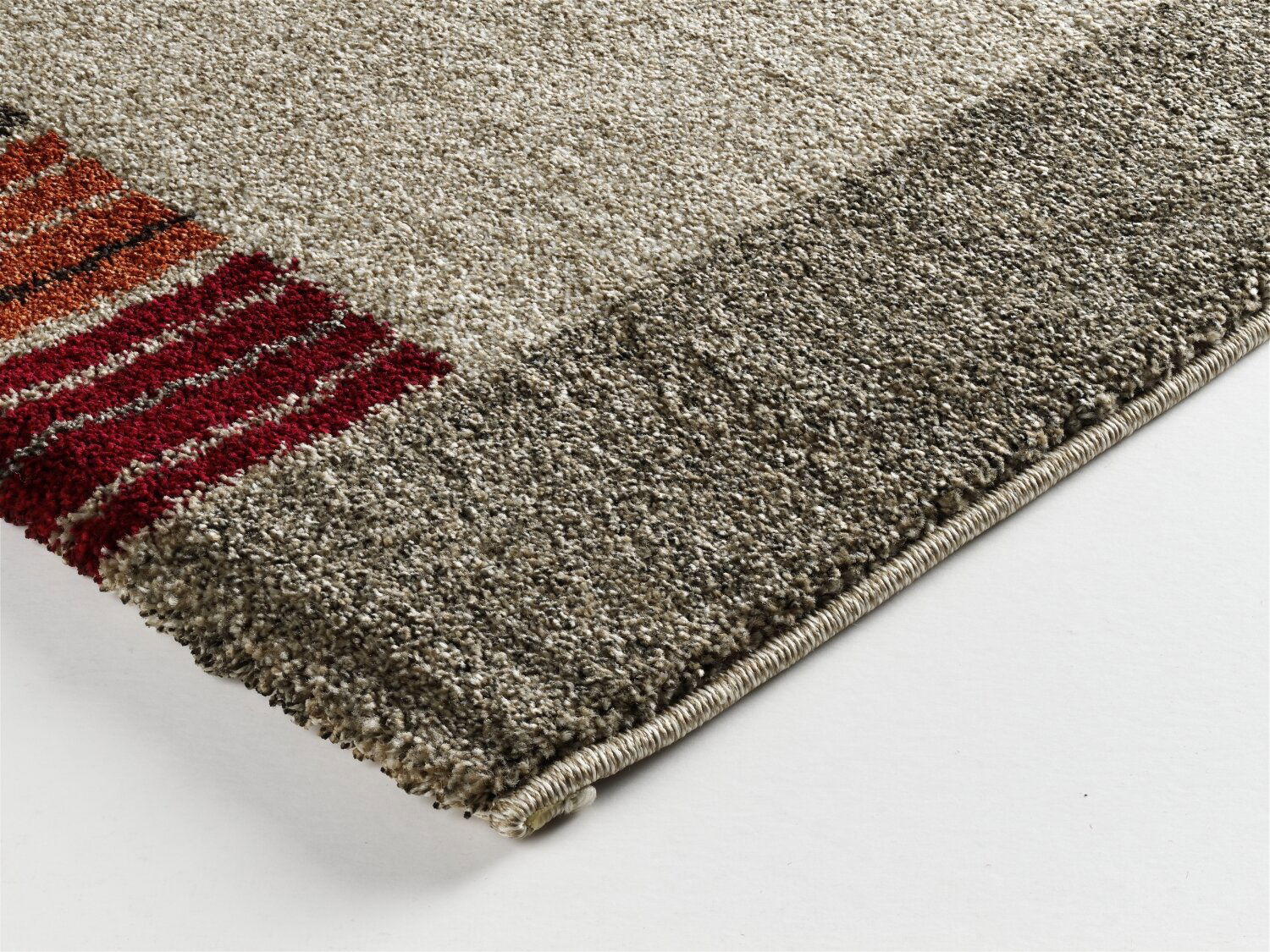 Nahaufnahme einer Ecke eines Teppichs mit grauen und roten Streifen, Perspektive von oben.