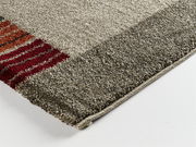 Nahaufnahme einer Ecke eines Teppichs mit grauen und roten Streifen, Perspektive von oben.