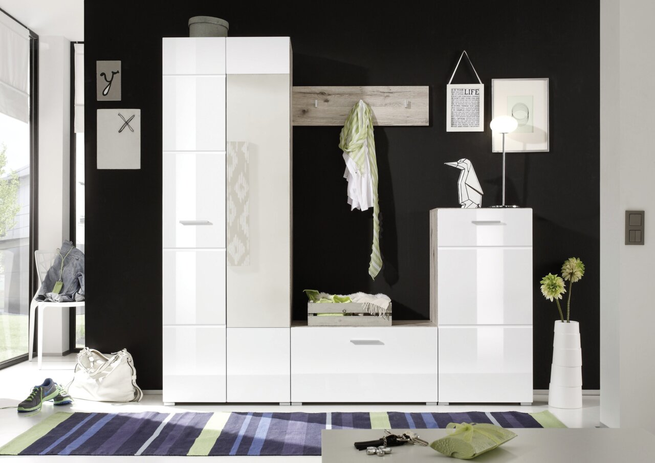 Moderne Garderobenkombination in Weiß mit Hochglanzfronten, bestehend aus einem hohen Schrank, einer Sitzbank mit Schublade und einem Hängeregal mit Haken, vor schwarzer Wand. Perspektive: Frontalansicht.