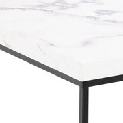 Nahaufnahme eines Couchtischs mit weißer Marmoroptik und schwarzem Metallrahmen, perspektivisch von der Ecke aufgenommen.