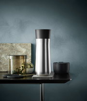 Eleganter Impulse Isolierbecher 0,35l in Edelstahloptik mit schwarzem Deckel, seitliche Perspektive auf einem Tisch arrangiert.