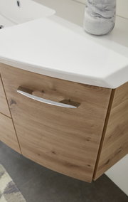 Nahaufnahme einer Badkombination mit Holzoptik und weißem Waschbecken, seitliche Perspektive