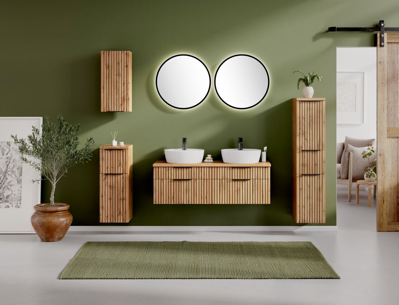 Moderne wastafelcombinatie met twee ronde spiegels, houten kasten en een groene wand, gezien van voren.