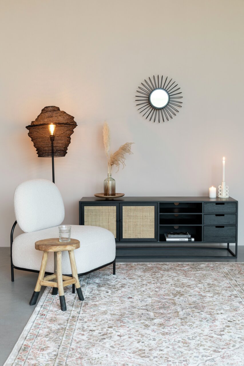Modernes Sideboard mit schwarzem Rahmen und geflochtenen Türen, dekoriert mit Kerzen und Vasen, aus seitlicher Perspektive fotografiert.