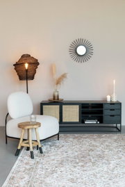 Modernes Sideboard mit schwarzem Rahmen und geflochtenen Türen, dekoriert mit Kerzen und Vasen, aus seitlicher Perspektive fotografiert.