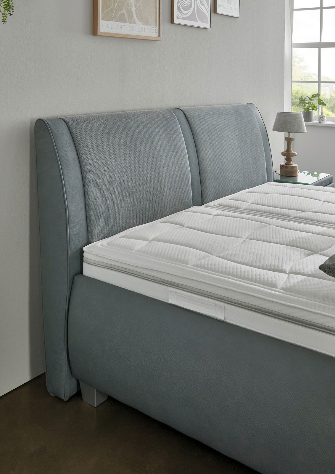 Graues Polsterbett mit elegantem Kopfteil, seitliche Perspektive