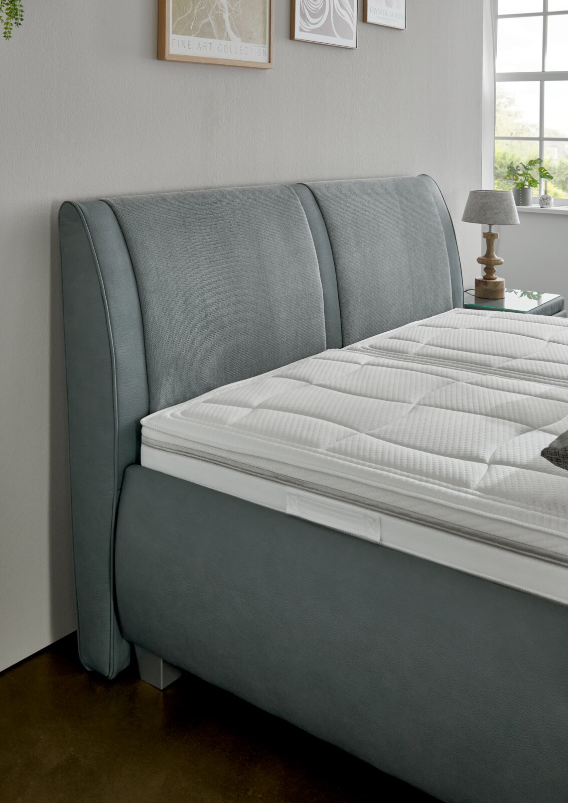 Graues Polsterbett mit elegantem Kopfteil, seitliche Perspektive