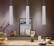Drie moderne, cilindervormige hanglampen in een stijlvol ingerichte ruimte, gezien vanuit het perspectief van een eettafel.