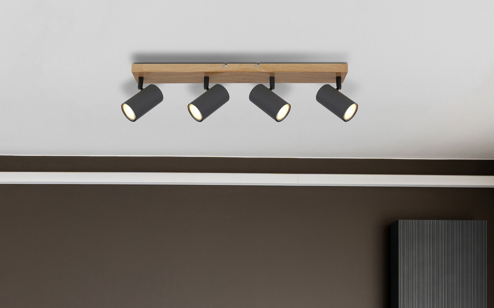 Deckenstrahler mit vier schwarzen, zylinderförmigen Leuchten an einer Holzleiste, Perspektive von unten
