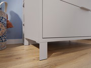 Nahaufnahme einer weißen Kommode auf Holzfußboden, seitliche Perspektive