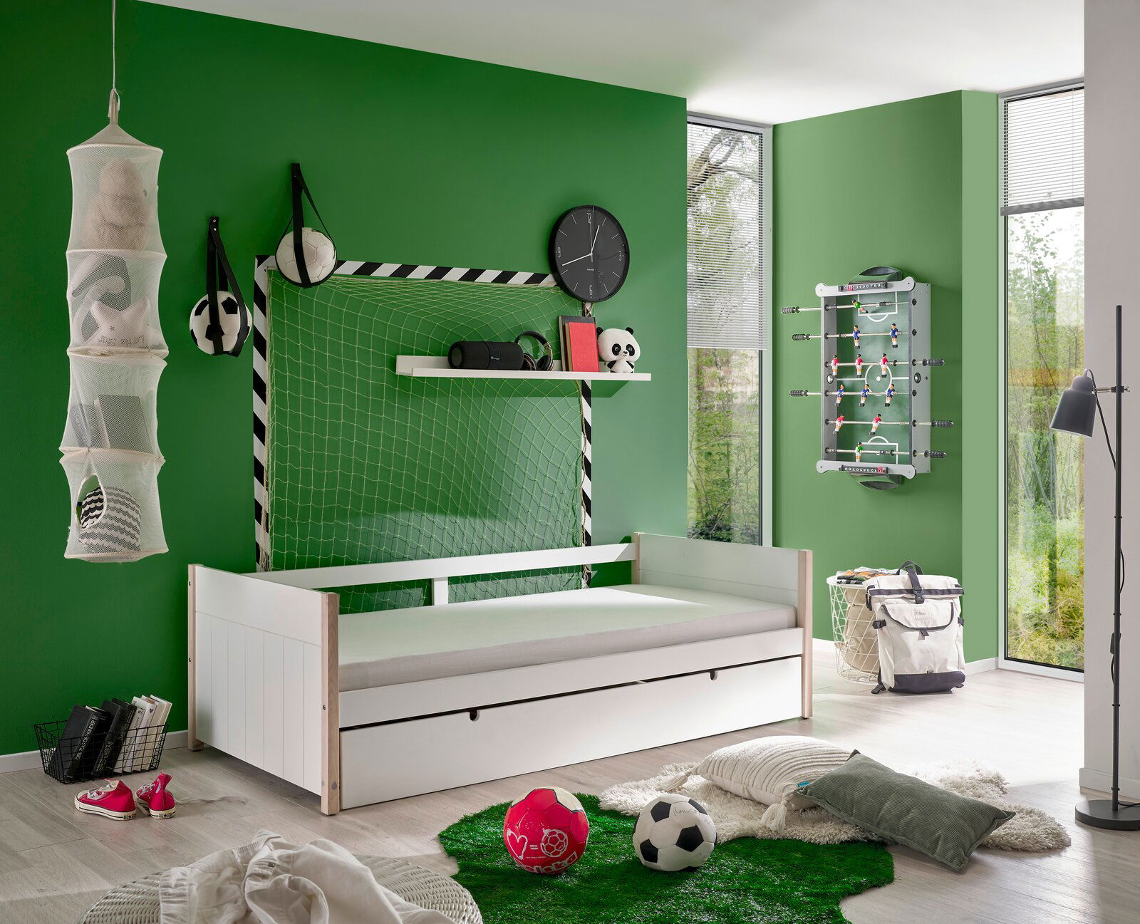 Jugendzimmer mit weißem Jugendbett, Fußball-Dekoration und grünem Teppich, seitliche Perspektive