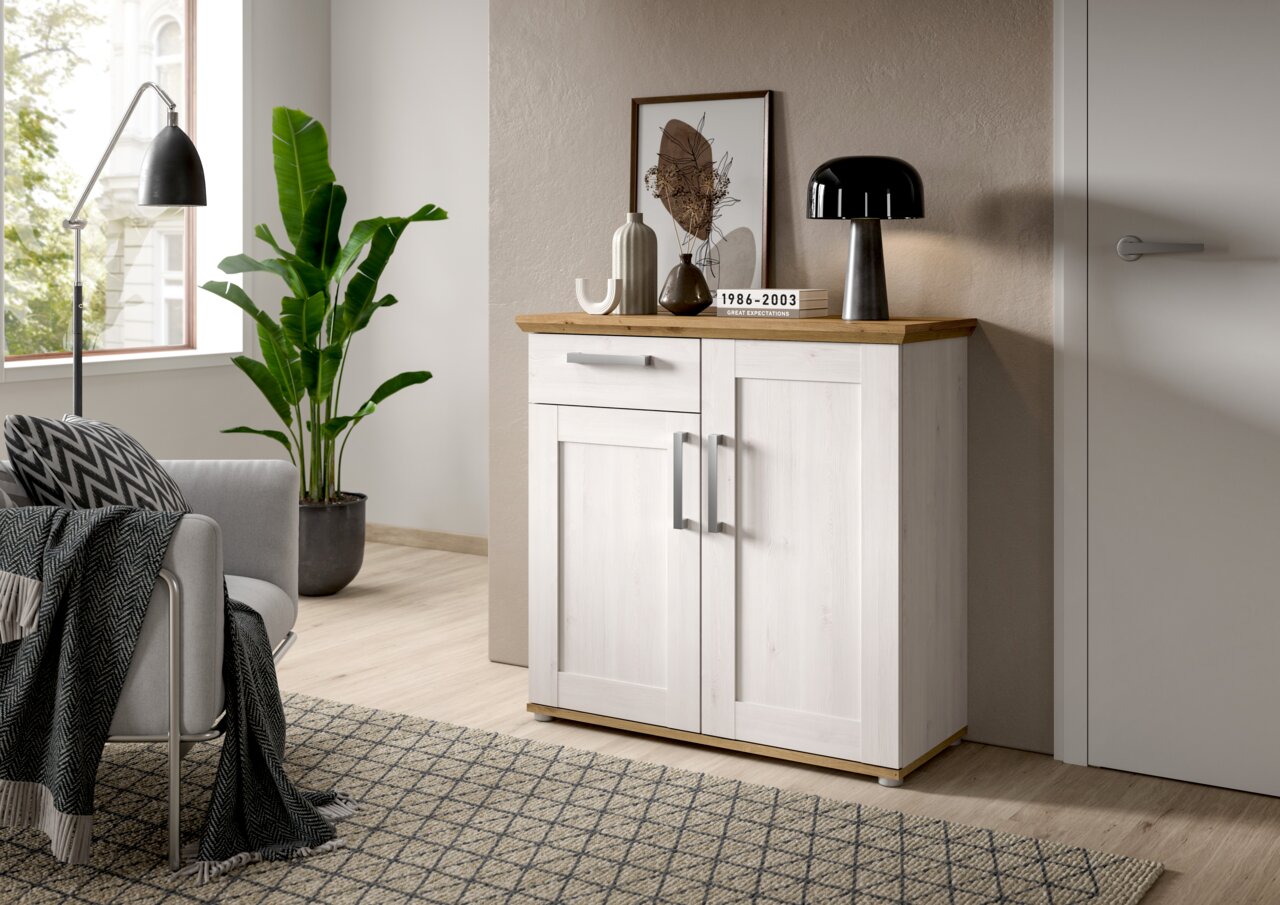 Kommode in heller Holzoptik mit zwei Türen und einer Schublade, dekoriert mit Vasen und einer Lampe, seitliche Perspektive