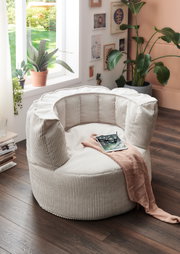 Großer, cremefarbener Sitzsack in einem gemütlichen Wohnzimmer, umgeben von Pflanzen und Dekorationen, aus der Seitenperspektive fotografiert.