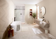Modernes Badezimmer mit freistehender Badewanne, mehreren Badteppichen in neutralen Farben und einem großen Spiegel, seitliche Perspektive.