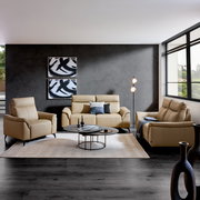 Wohnzimmeransicht mit beigem Ledersofa-Set bestehend aus einem 3-Sitzer, einem 2-Sitzer und einem Sessel, vor einer grauen Wand mit moderner Kunst, auf einem hellen Teppich mit Couchtisch und Stehlampe.