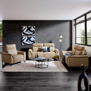 Een blik op de woonkamer met een beige lederen bankstel, bestaande uit een driezitsbank, een tweezitsbank en een fauteuil, tegen een grijze muur met moderne kunst, op een licht tapijt met een salontafel en een staande lamp.