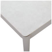 Close-up van een moderne salontafel met een lichtgekleurd tafelblad en afgeronde hoeken, gezien van bovenaf.