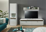 Modernes Wohnzimmer mit einem weißen Wandboard über einem großen Flachbildfernseher, flankiert von einem hohen weißen Schrank und einem weißen TV-Schrank mit Holzdetails. Perspektive von vorne.