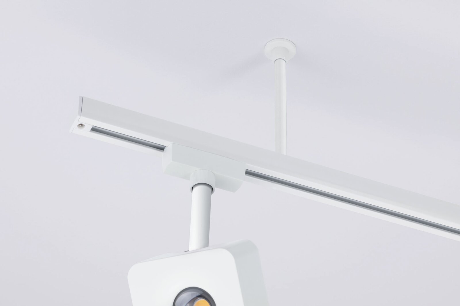 Weiße Decken-Stromschiene mit abgehängter Leuchtenhalterung und Spot, Detailansicht aus Untersicht in leichter Schrägperspektive