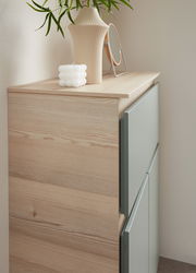 Nahaufnahme eines Unterschranks mit Abdeckplatte aus Holz, dekoriert mit einer Vase, einem Spiegel und einer Kerze, seitliche Perspektive.