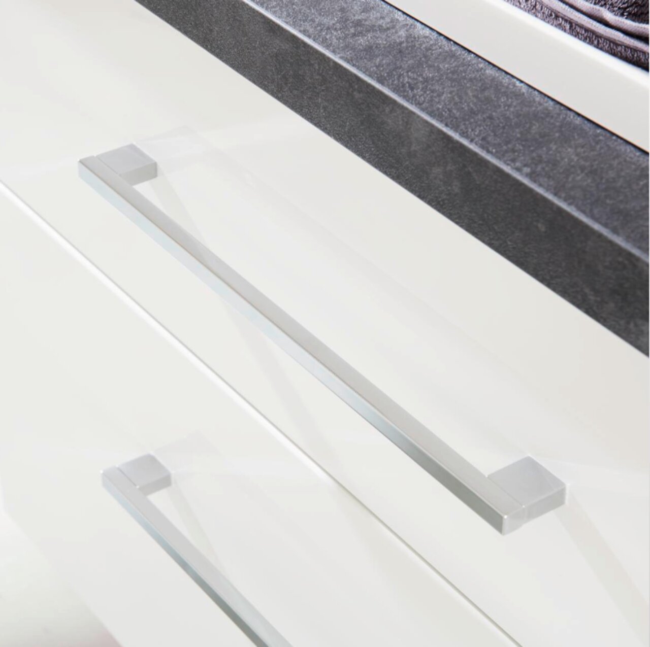 Nahaufnahme einer Badkombination mit weißen Schubladen und modernen, silbernen Griffen aus der Vogelperspektive.