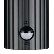 Nahaufnahme einer schwarzen Außenwandleuchte mit geriffelter Oberfläche und integriertem Bewegungssensor.