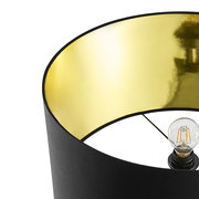 Nahaufnahme einer Stehleuchte mit schwarzem Lampenschirm und goldener Innenseite, von oben betrachtet.