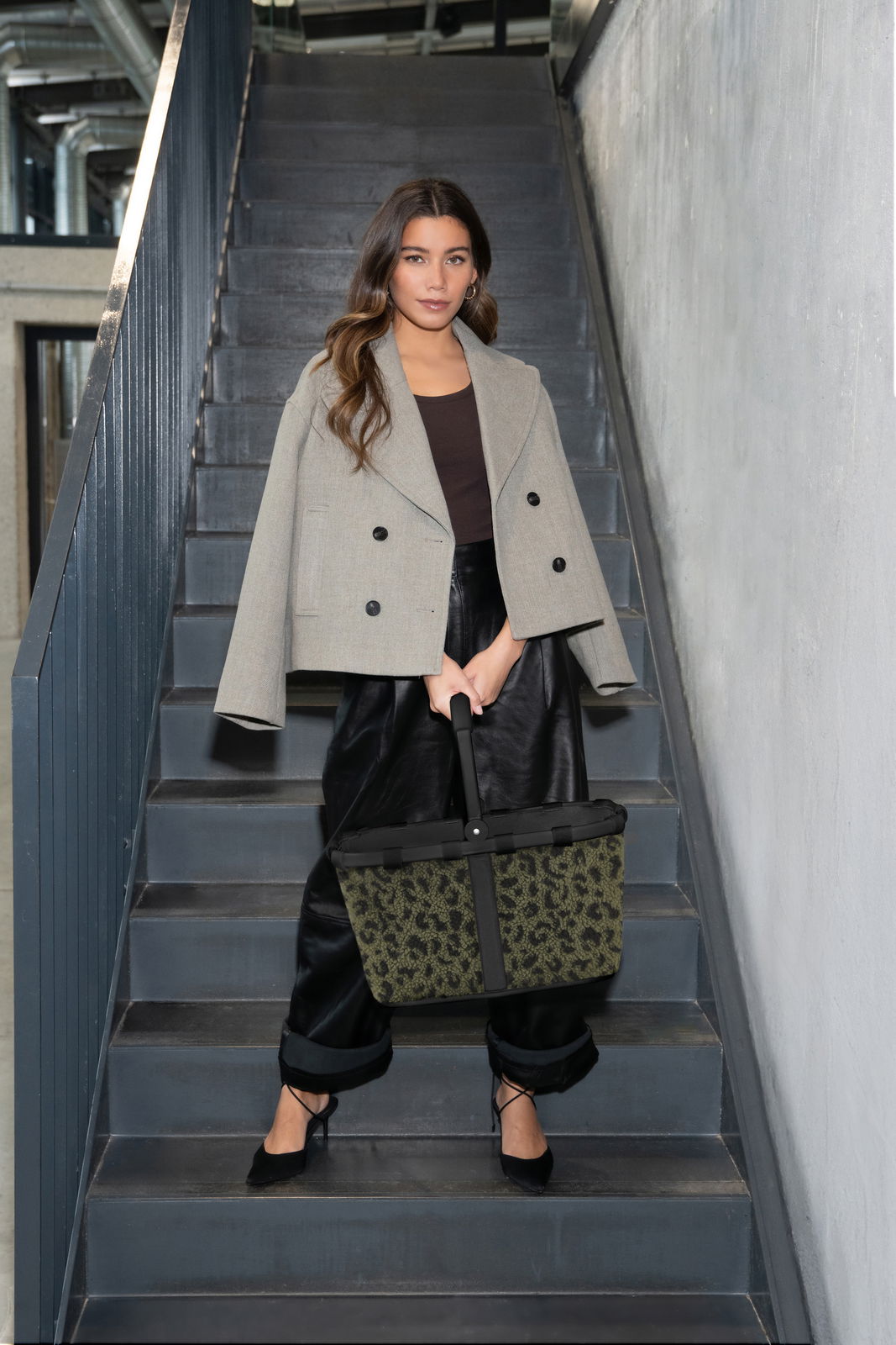 Reisenthel Carrybag Leo Olive TEDDY Frau auf Treppe mit grün-schwarzer Tragetasche, Frontalansicht