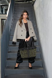 Frau auf Treppe mit grün-schwarzer Tragetasche, Frontalansicht