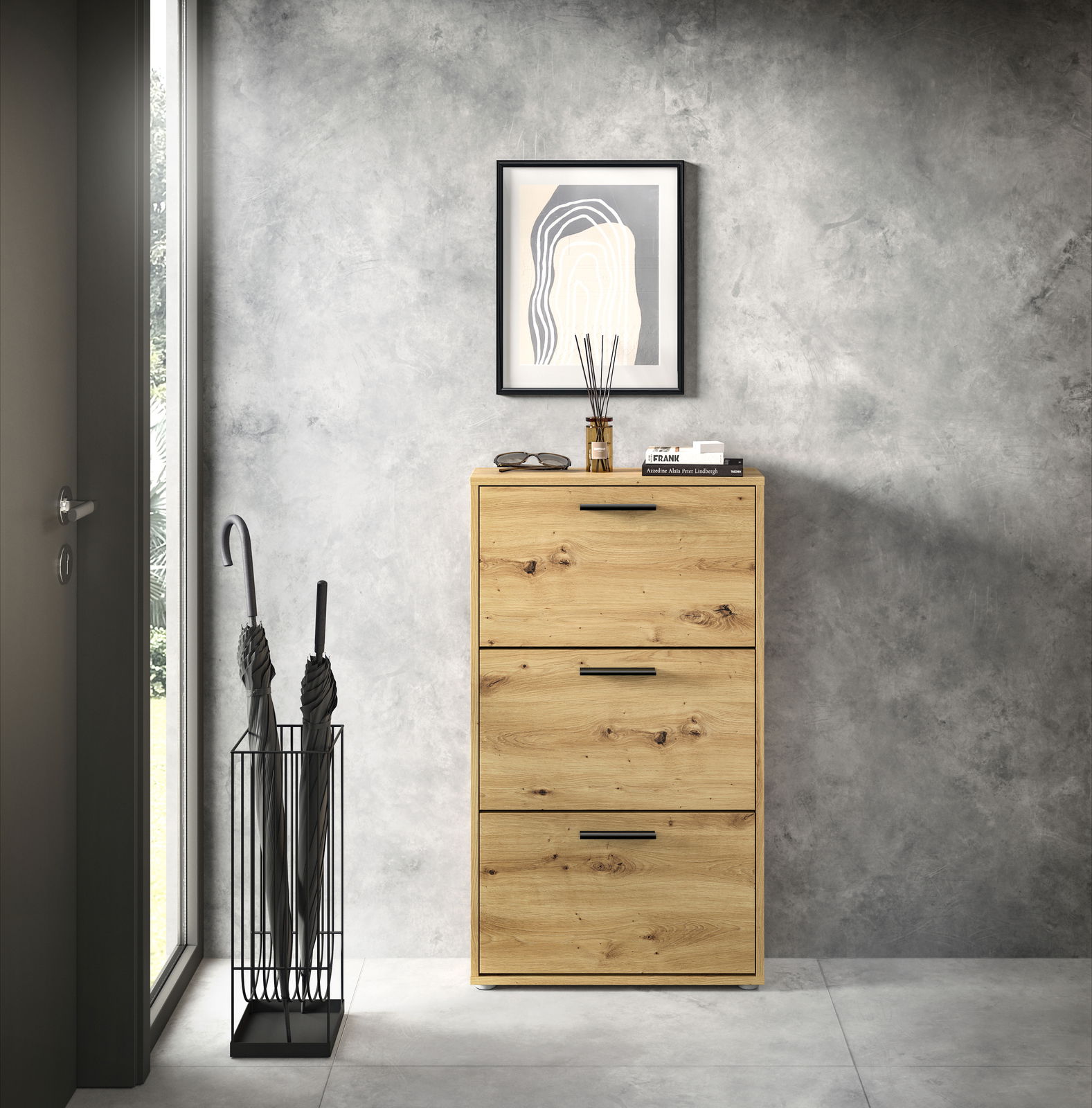 Schuhkipper aus Holz mit drei Klappen, frontal fotografiert, neben einem Regenschirmständer und unter einem gerahmten Bild an der Wand.