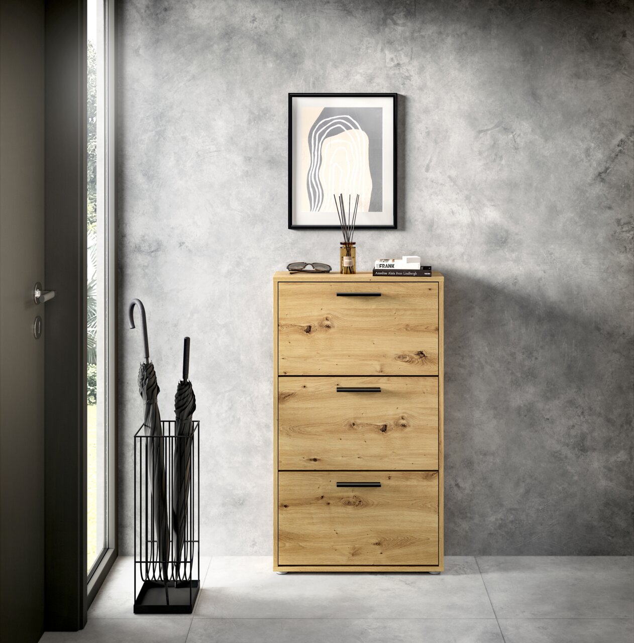 Schuhkipper aus Holz mit drei Klappen, frontal fotografiert, neben einem Regenschirmständer und unter einem gerahmten Bild an der Wand.