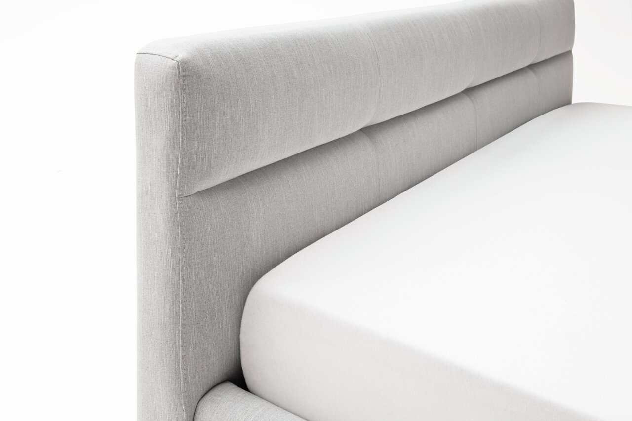 Graues Polsterbett mit gepolstertem Kopfteil, seitliche Perspektive