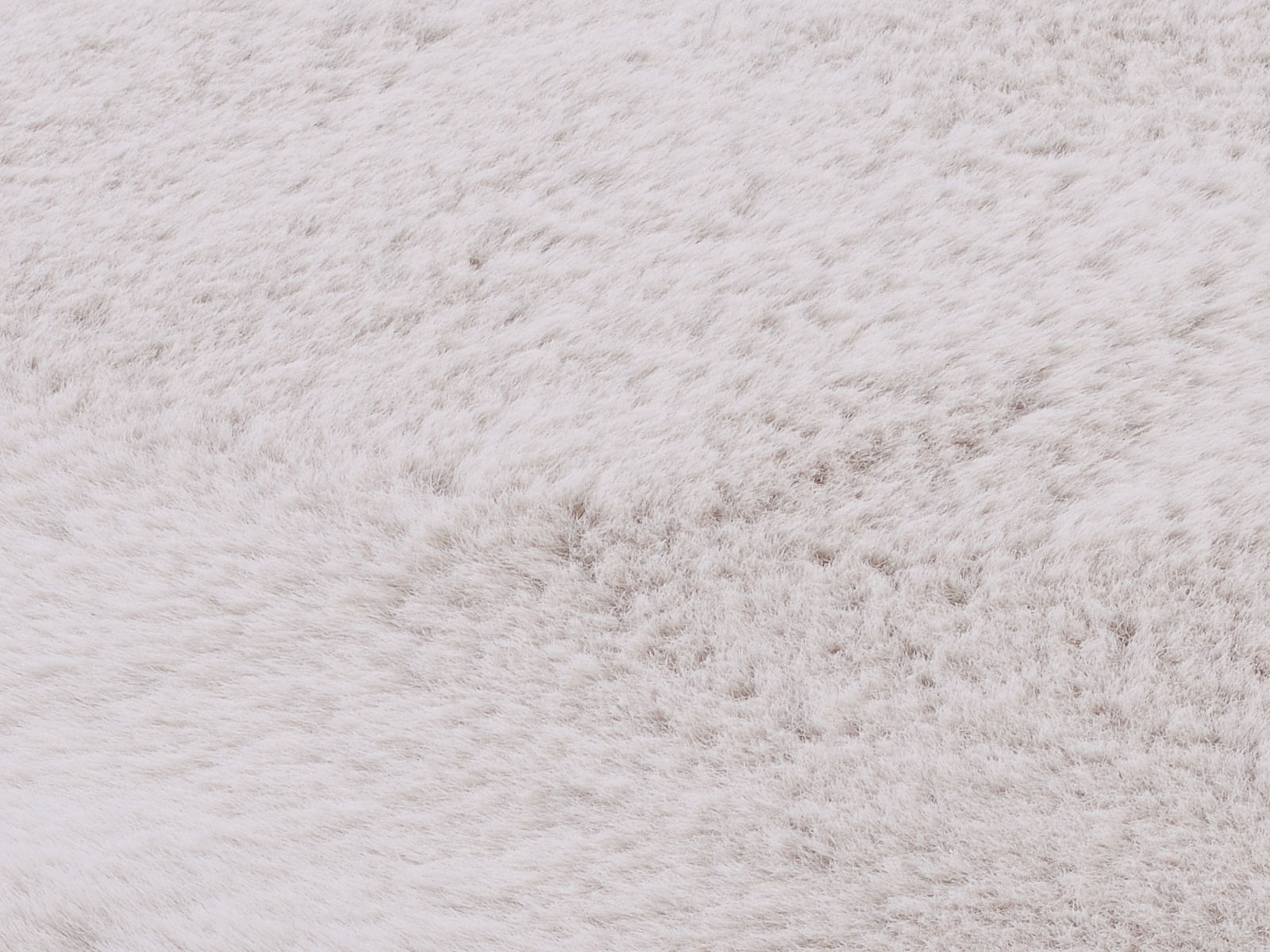 Nahaufnahme eines weißen Fellteppichs, die die weiche Textur und das flauschige Material zeigt.