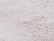 Nahaufnahme eines weißen Fellteppichs, die die weiche Textur und das flauschige Material zeigt.