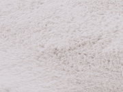 Nahaufnahme eines weißen Fellteppichs, die die weiche Textur und das flauschige Material zeigt.