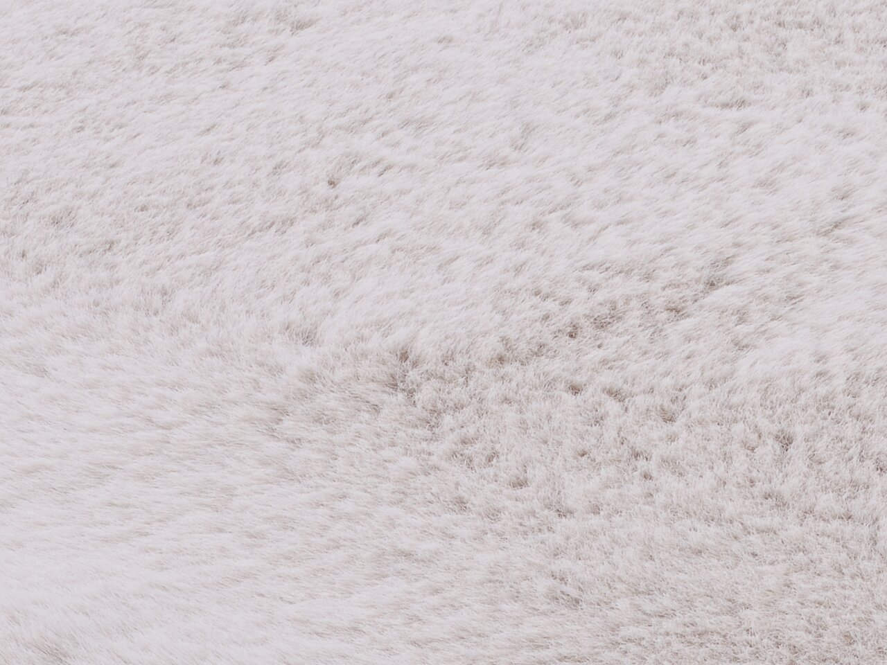 Nahaufnahme eines weißen Fellteppichs, die die weiche Textur und das flauschige Material zeigt.