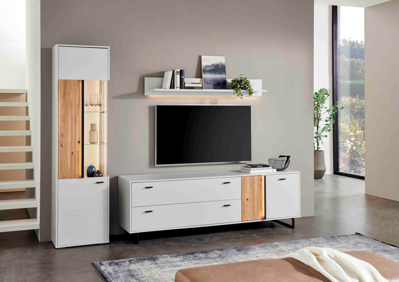 Frontale Ansicht eines modernen TV-Lowboards der Marke Hom'in, Modell GLASGOW, in Weiß mit Holzelementen und schwarzen Griffen, platziert in einem stilvollen Wohnzimmer.