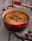 Roter runder Le Creuset Bräter, 24 cm, mit gebackenem Kuchen, von oben fotografiert, auf rustikalem Holztisch mit Schokoladenstücken und Vanilleschoten.