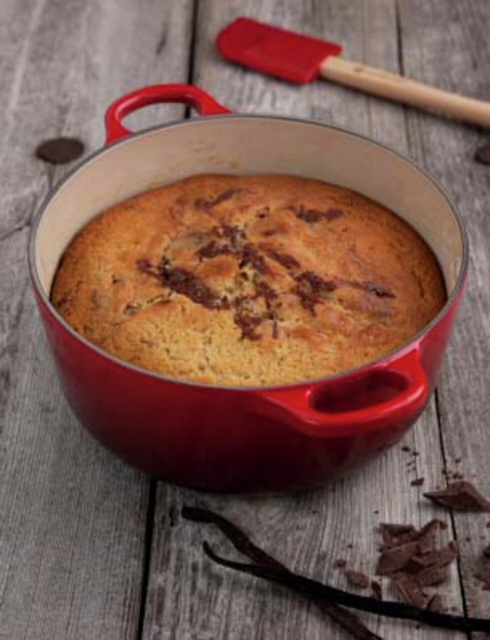 LE CREUSET Bräter Rund 24cm Kirschrot SIGNATURE Roter runder Le Creuset Bräter, 24 cm, mit gebackenem Kuchen, von oben fotografiert, auf rustikalem Holztisch mit Schokoladenstücken und Vanilleschoten.