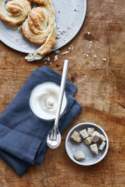 Latte Macchiato-Löffel Nuova auf einem Holztisch, neben einem Glas mit Milchschaum und Gebäck, aus der Vogelperspektive.