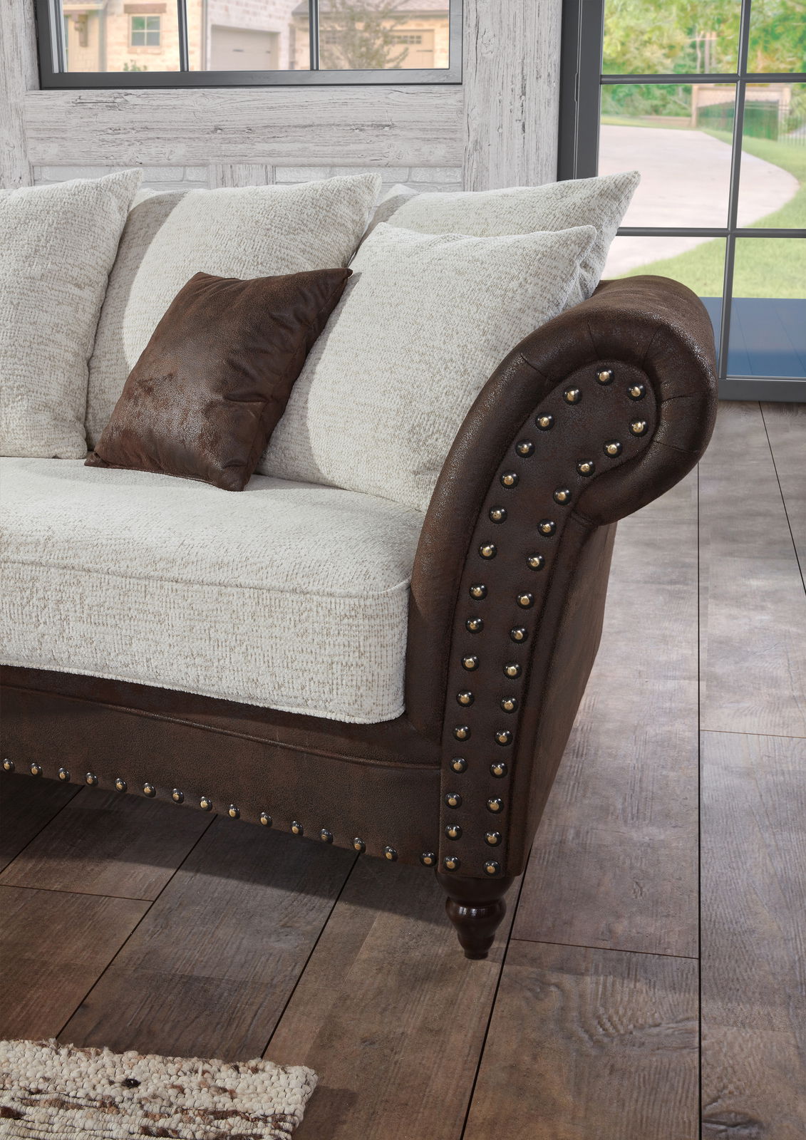 Detailansicht eines Megasofas mit runden Armlehnen, braunem Lederbezug und hellen Kissen in einem gemütlichen Wohnzimmer.