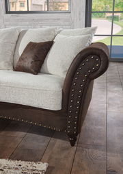 Detailansicht eines Megasofas mit runden Armlehnen, braunem Lederbezug und hellen Kissen in einem gemütlichen Wohnzimmer.