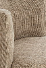 Nahaufnahme eines Sessels mit beige-braunem Stoffbezug, seitliche Perspektive.