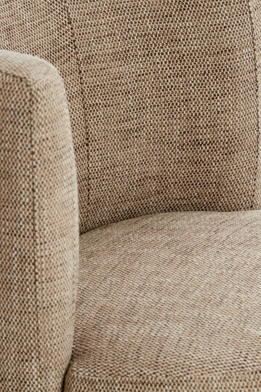 Nahaufnahme eines Sessels mit beige-braunem Stoffbezug, seitliche Perspektive.