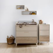 Zwei Kommoden in einem modernen Kinderzimmer, frontal fotografiert. Die linke Kommode ist breiter und hat eine Wickelauflage, während die rechte schmaler ist. Beide haben eine Kombination aus glatten und geriffelten Schubladenfronten in neutralen Farben.