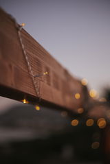 Nahaufnahme einer Outdoor-Solarlichterkette, die um einen Holzbalken gewickelt ist, mit unscharfem Hintergrund in der Abenddämmerung.